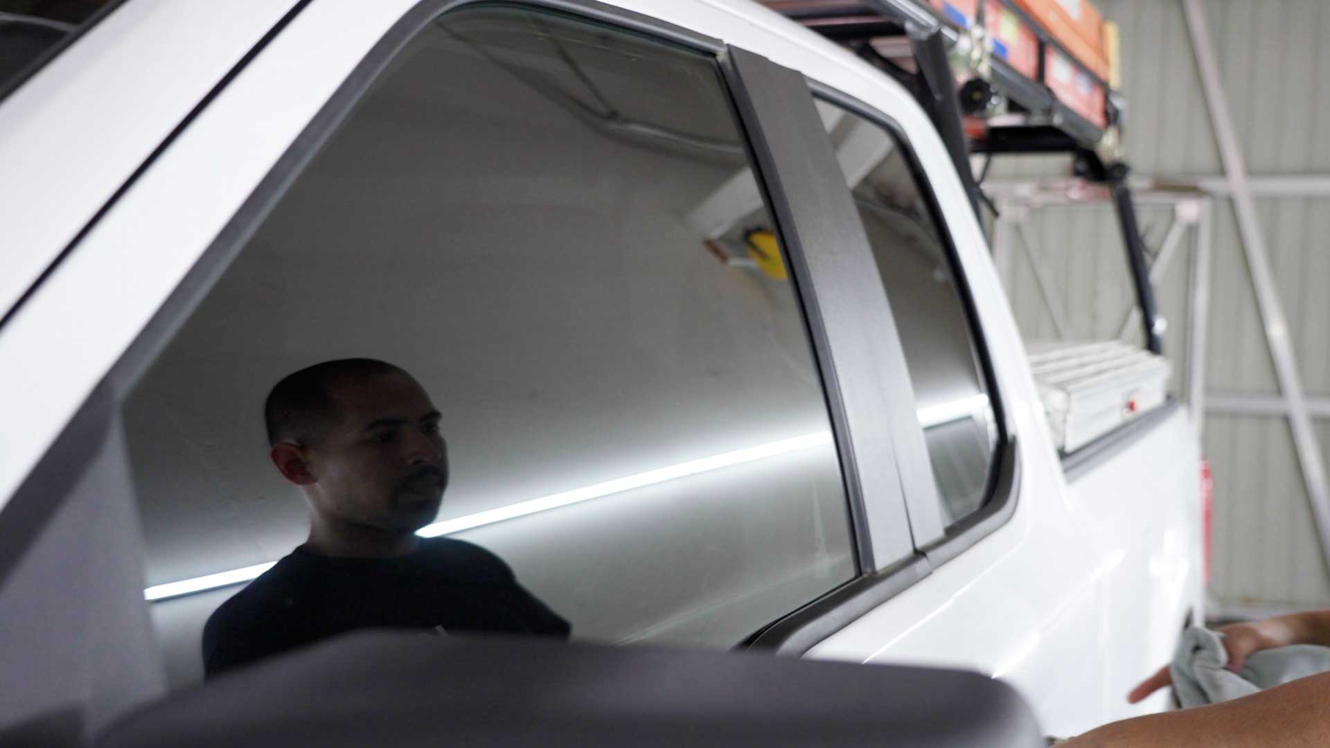 Technician cleaning a freshly installed ceramic window tint in DE